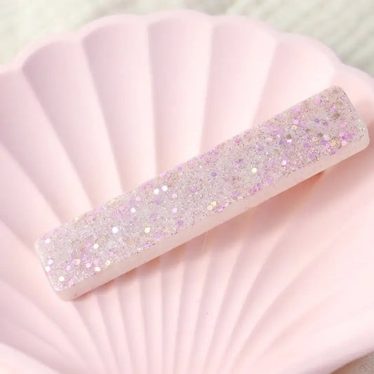 Helmiäisglitter hiusklipsi alustalla.